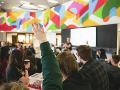 Group of people in room with person raising their hand