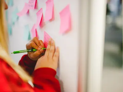 people sticking sticky notes to a whiteboard